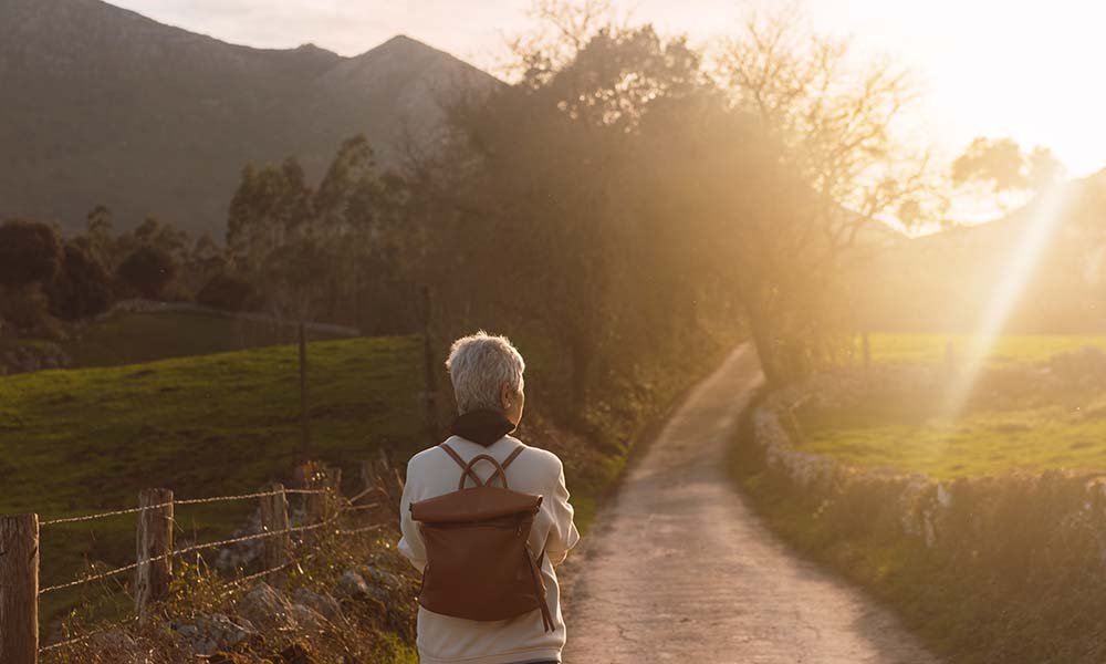 A woman walks toward the mountains and the sun, illustrating successful hip replacement surgery.